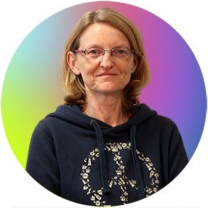 Auf dem Bild ist Frau Sabine Hilbers. Sie trägt einen dunkelblauen Hoodie mit einem dekorativen Muster.